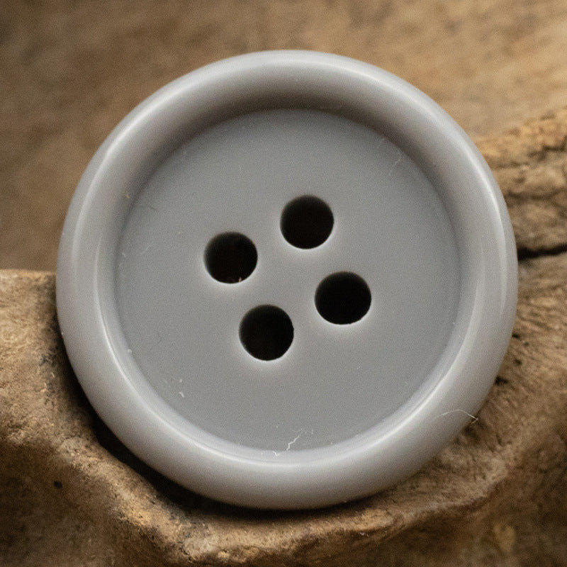 Pale light gray resin suit button with four holes, solid color front