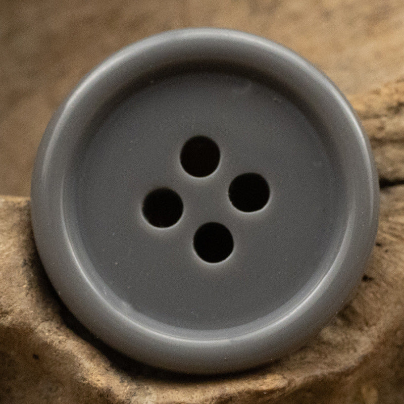 Light gray resin suit button with four holes, solid color front