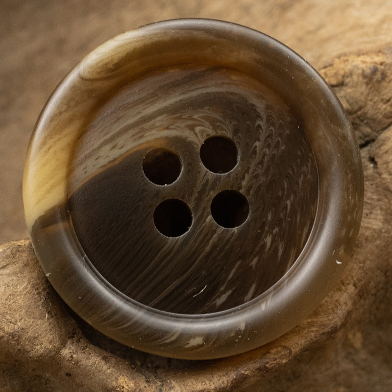 Brown round resin button with four holes and dark marbled swirls