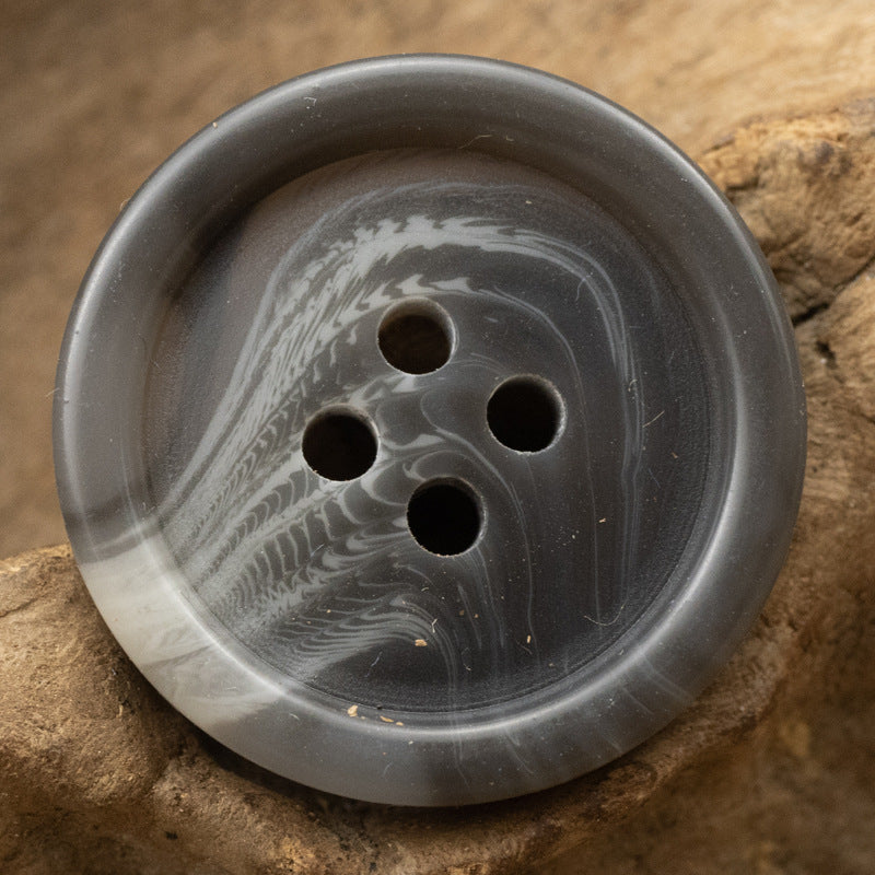 Dark gray round resin button with four holes and light marbled streaks