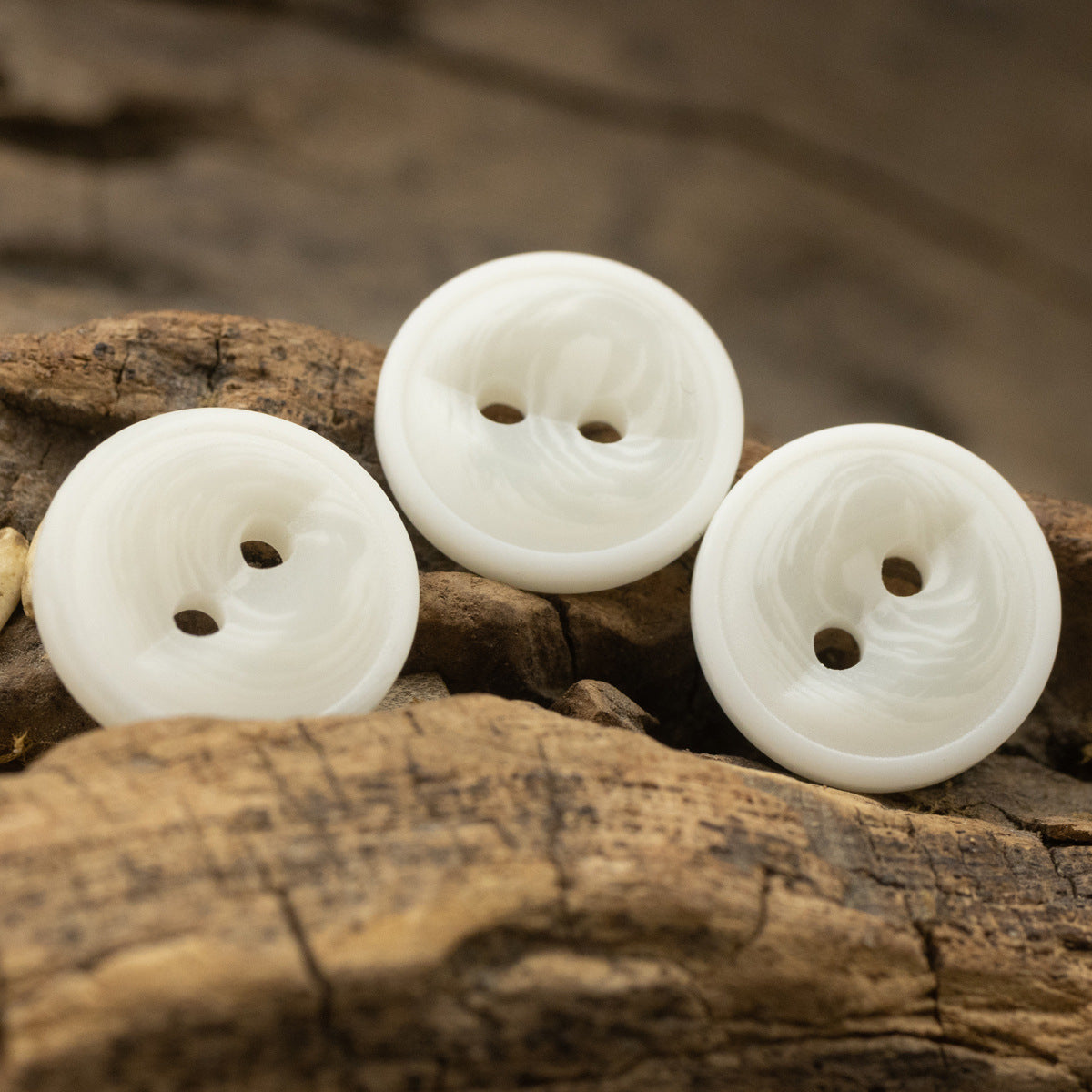 Set of three off-white resin buttons with two holes, fish-eye shape
