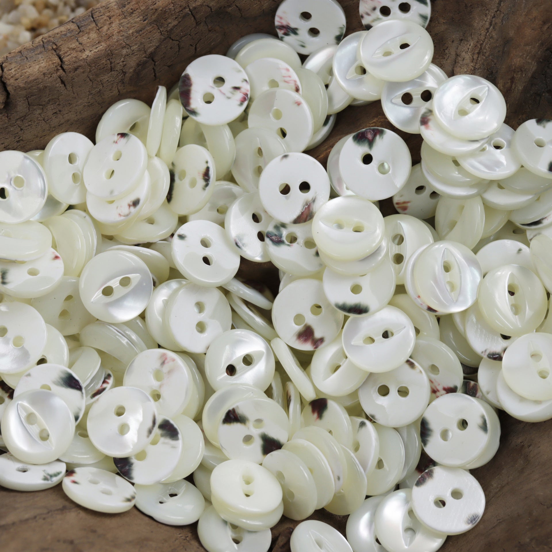 Two-hole natural shell buttons, mostly white with subtle speckled marbling