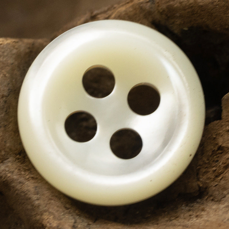 Large beige 4-hole shell button, round face close-up