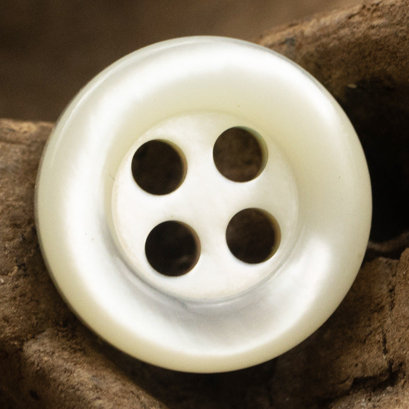 Beige 4-hole shell button front close-up, smooth round shape