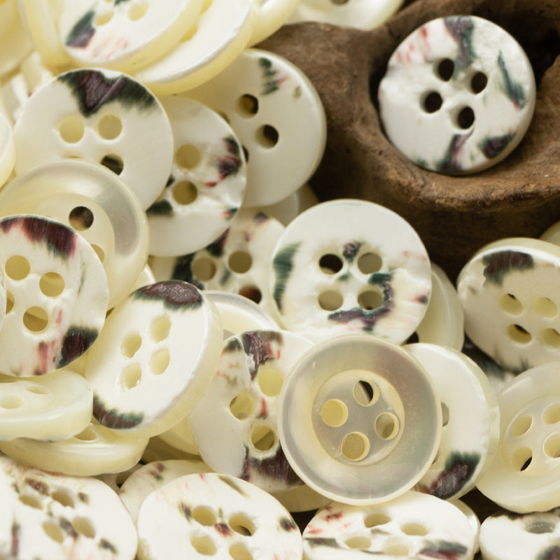 Natural white shell buttons with subtle speckles, round 4-hole style.