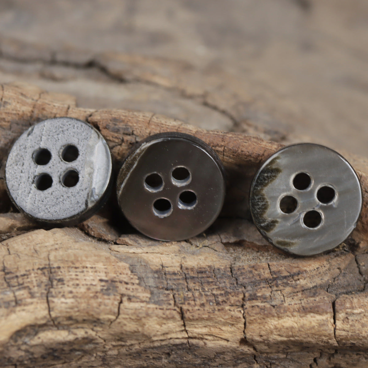 Dark blue shell buttons with four holes, 11.5mm, on wood