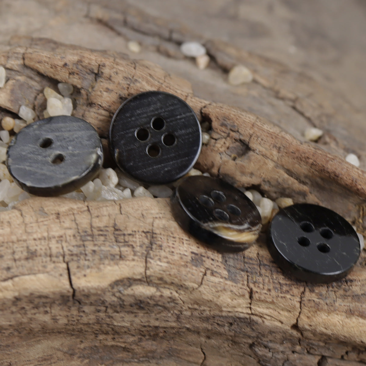 Schwarze Hemdknöpfe mit 4 Löchern auf Holzbrett, matte Oberfläche