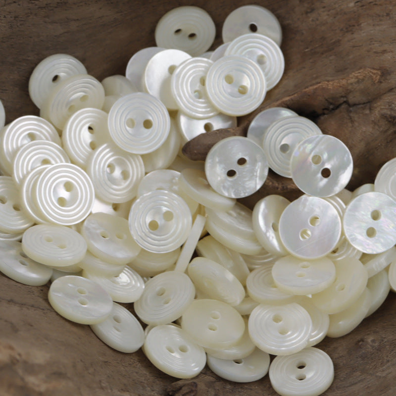 Natural white two-hole shell buttons with spiral swirl texture, leaf-shaped fronts
