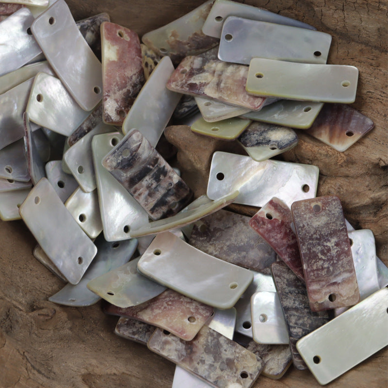 Assorted mother-of-pearl shell buttons, varied tones; mostly rectangular pieces with holes