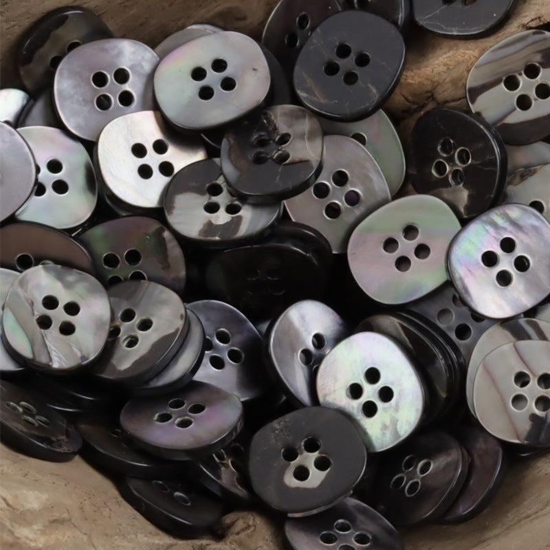 Assorted pearl shell buttons pile, iridescent and dark black, 4-hole designs