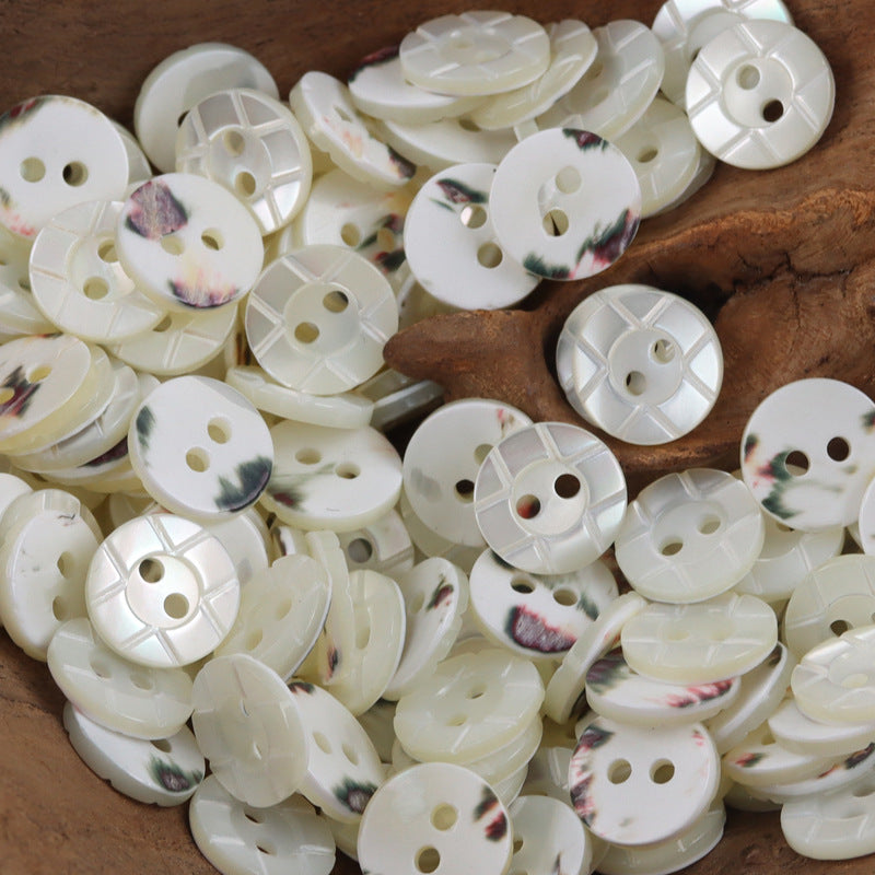 White natural shell buttons, round 2-hole with floral mottling and geometric embossed spokes