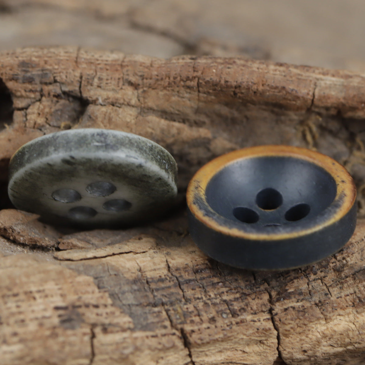 Two vintage 4-hole buttons with brown-edged rim, dark blue and gray tones
