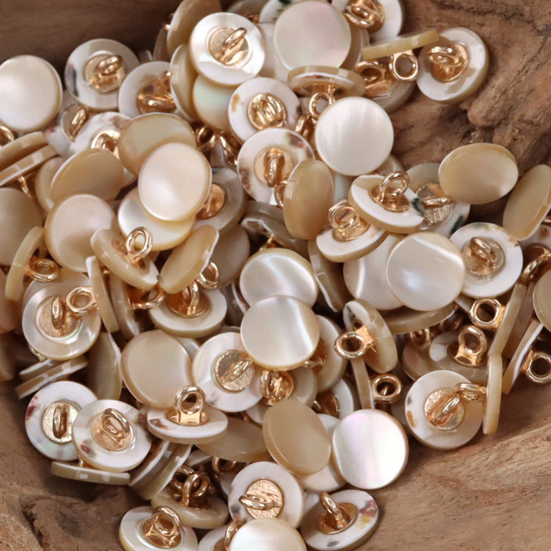 Assorted beige shell buttons with metal shanks, close-up of several pieces