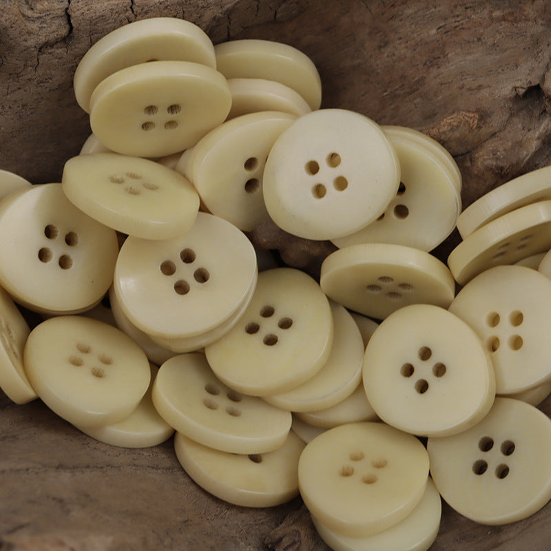 Pile of beige irregular bowl-shaped corozo buttons with 4-hole design (multiple buttons)