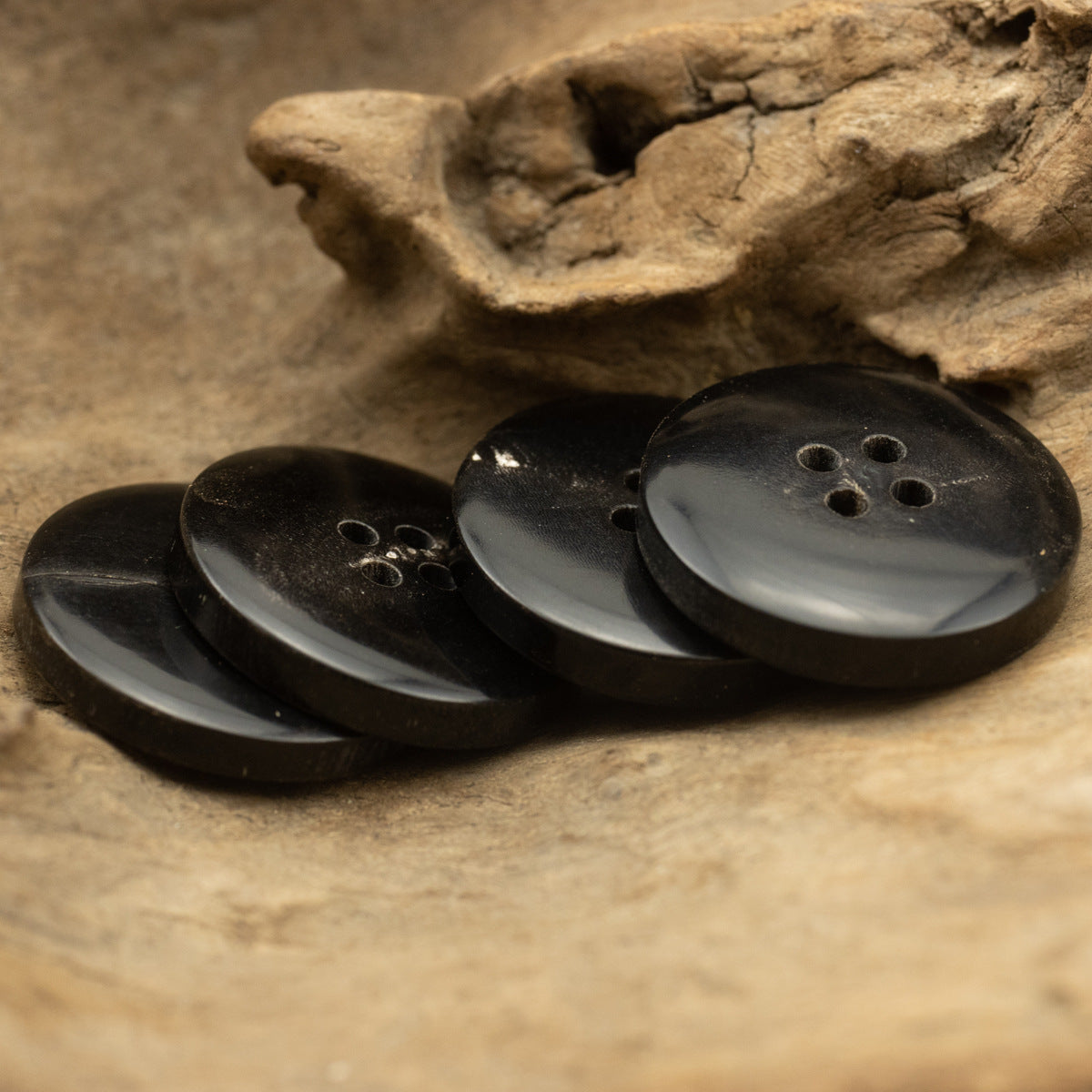 Black horn-style button set with four-hole faces, close-up stack