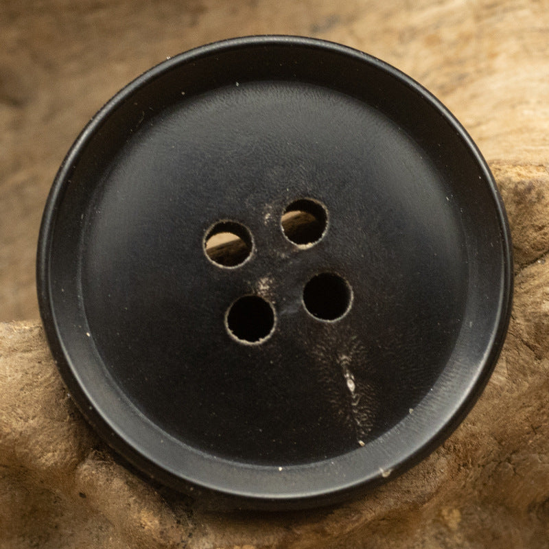 Black 4-hole button, horn-style surface with subtle sheen
