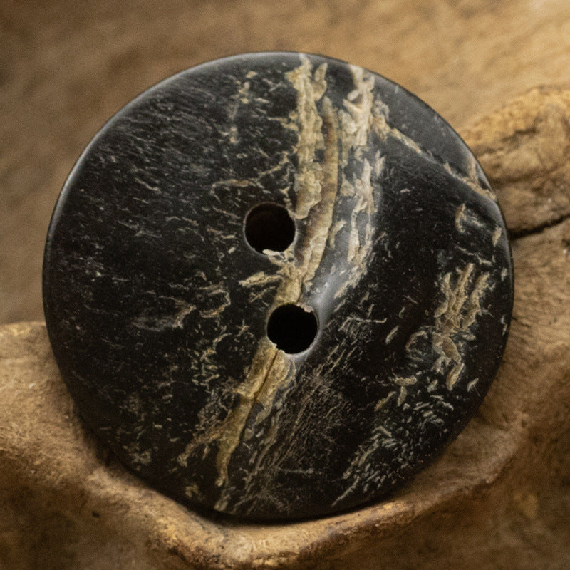 Black horn button, rough uneven surface, 2-hole design with dark mottled markings