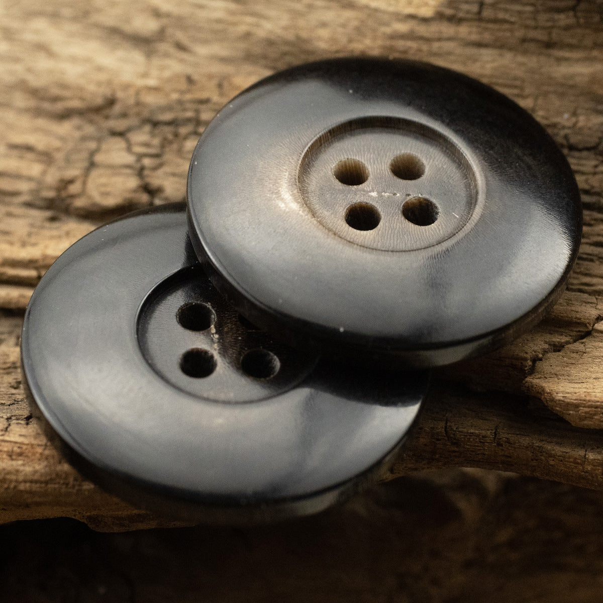 Natural black horn buttons, 4-hole front, matte finish, angled view