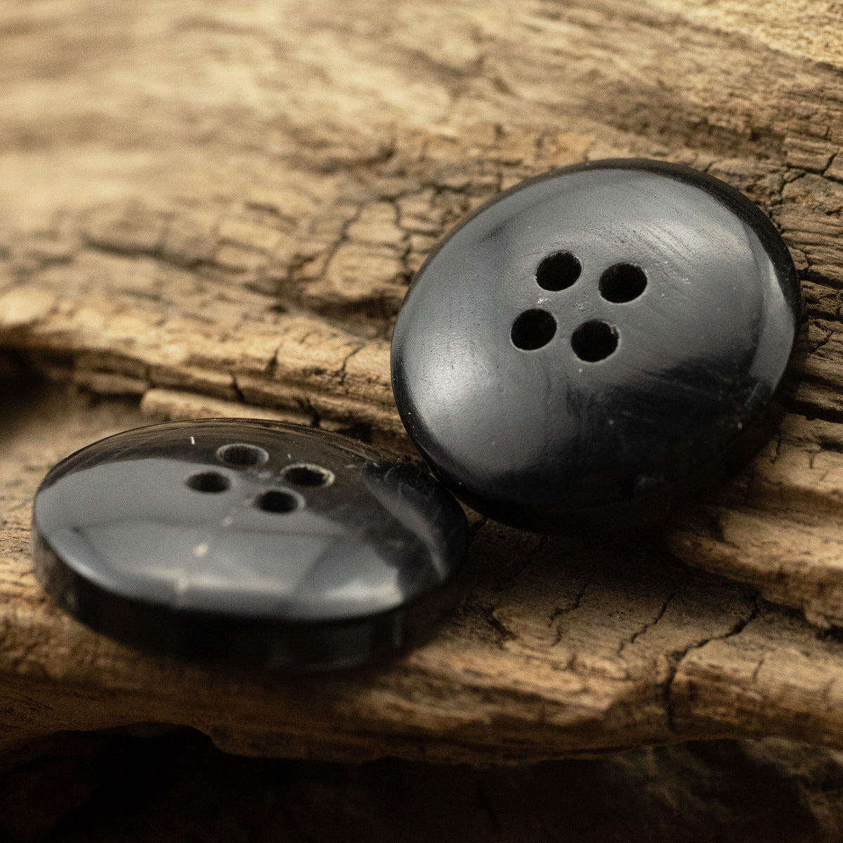 Black four-hole horn buttons, domed front with 4 holes, second button beside it