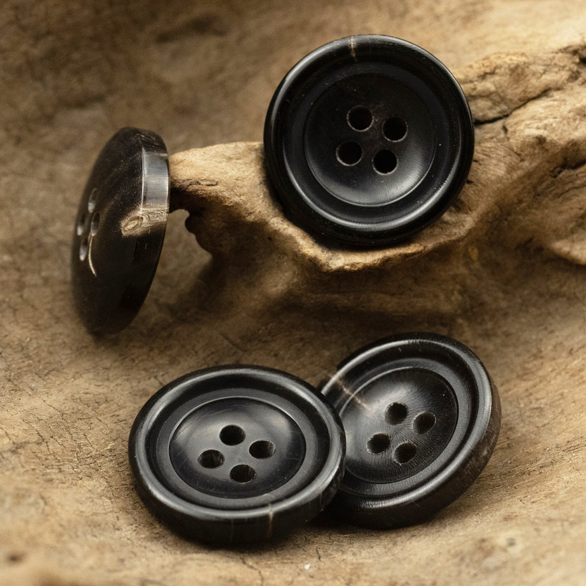 Pair of black four-hole horn buttons, front and side view, 4 holes each