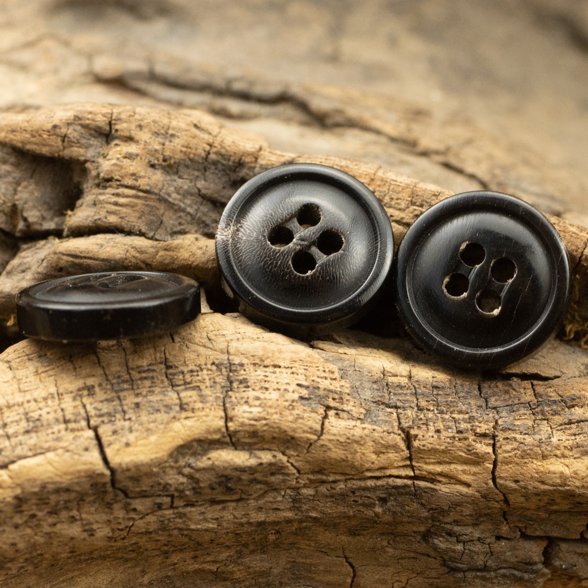 Natural black horn buttons with four holes, plus small clear cover piece