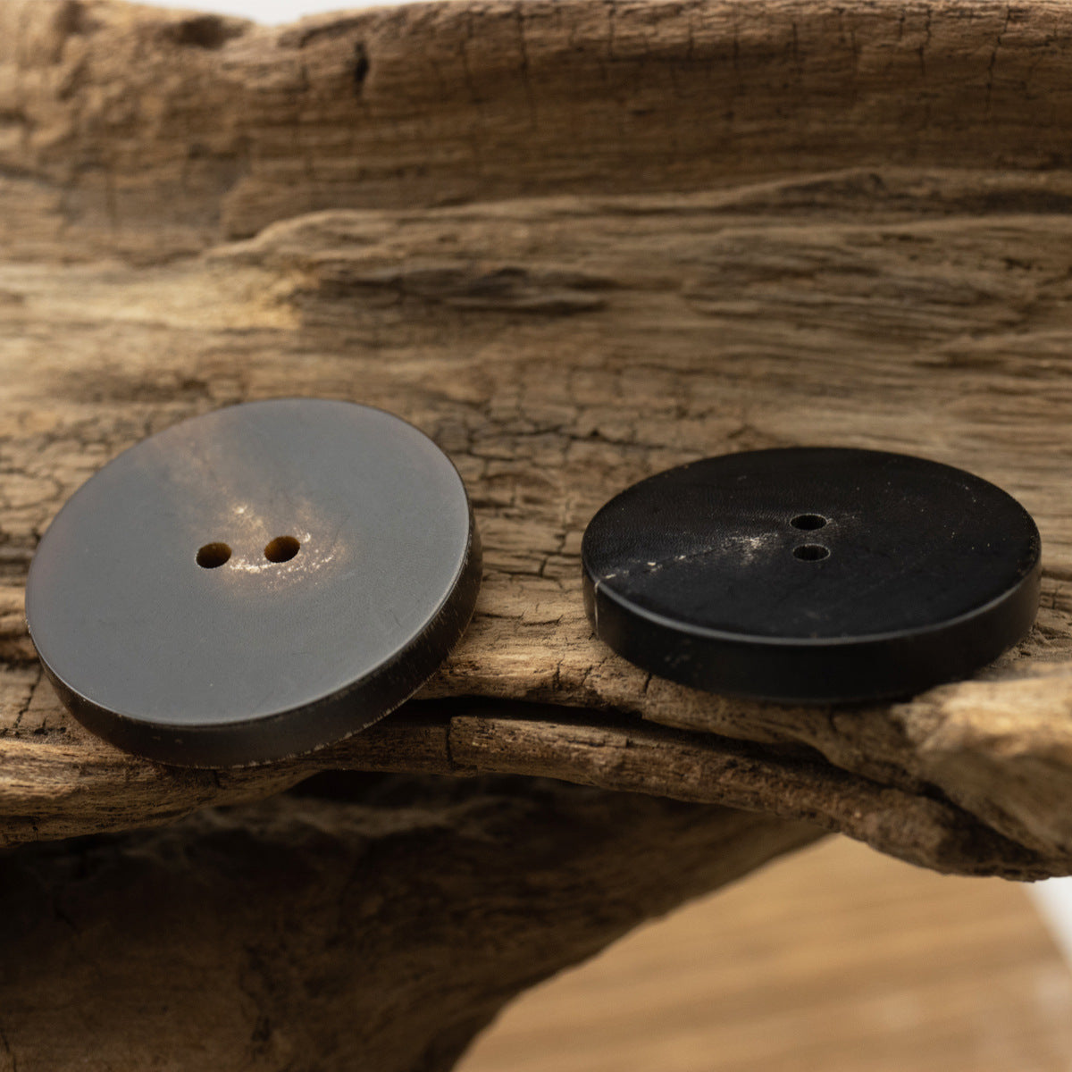 Flat two-hole horn buttons, one dark and one lighter, 15–28mm