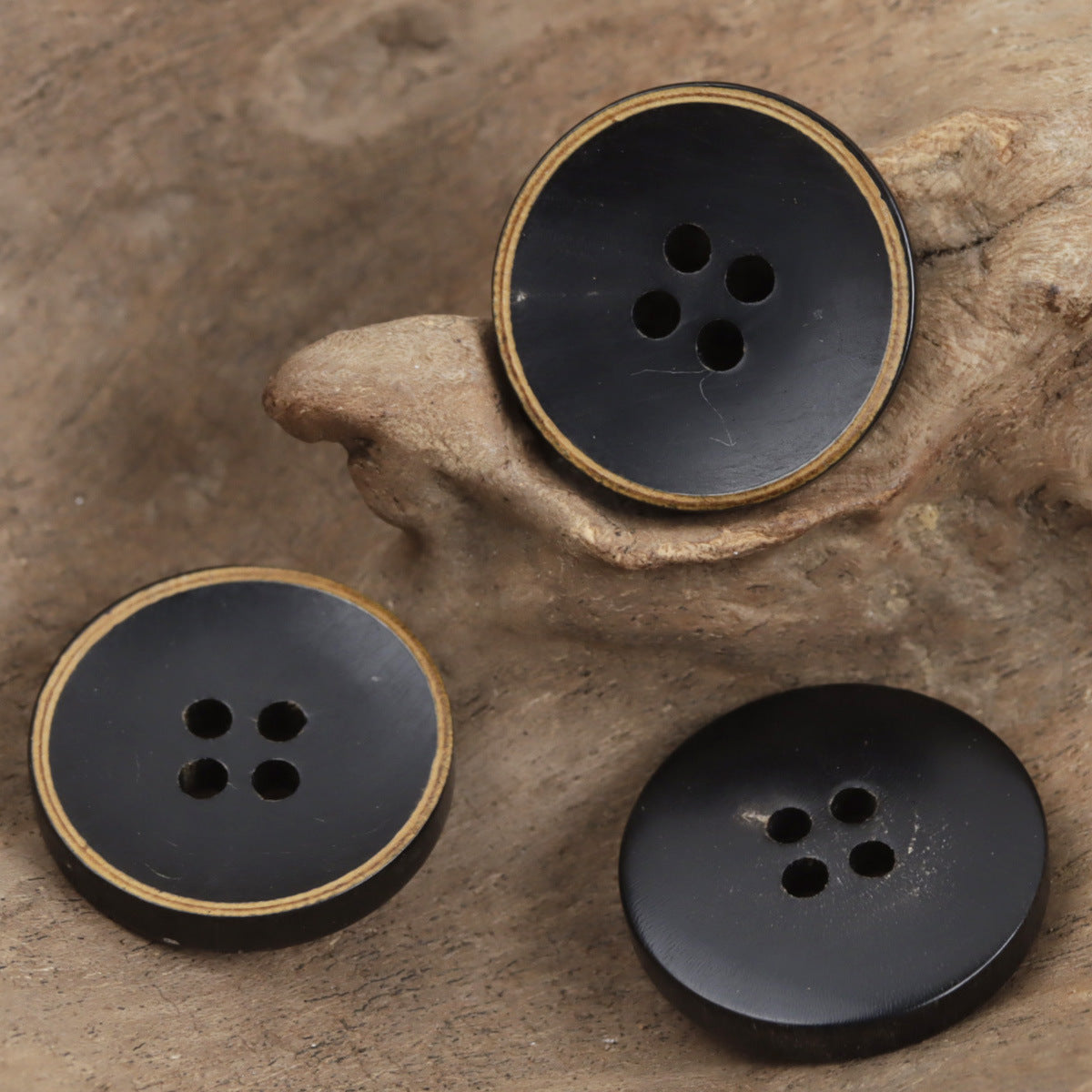 Four-hole horn bowl buttons set, dark finish with gold rim, three buttons shown