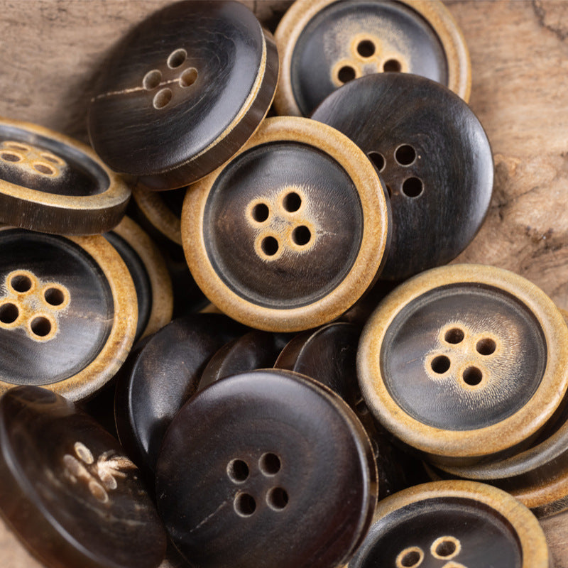 Group of dark four-hole horn buttons with tan rims, mixed angles