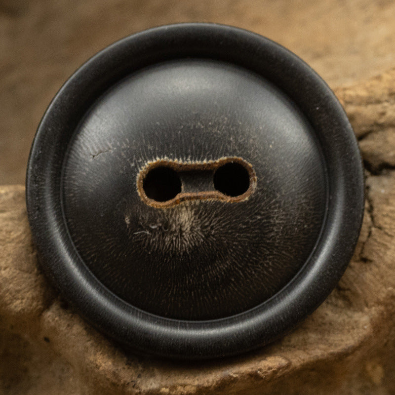 Black horn button with two holes, close-up