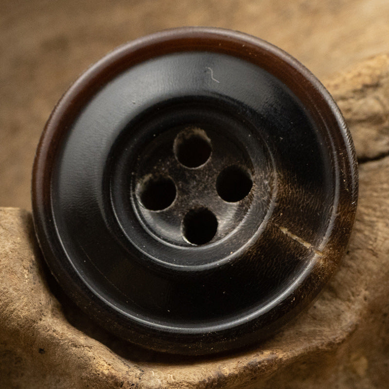 Dark 4-hole horn button with brown edge, vintage 15–25mm, close-up