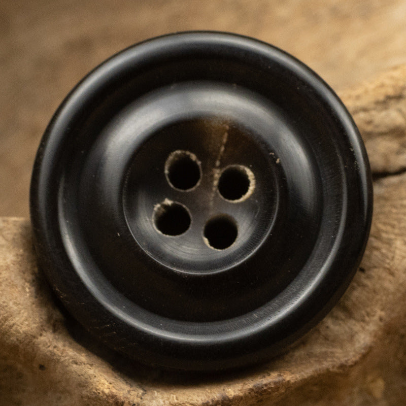 Black 4-hole horn button, vintage 15–25mm, close-up