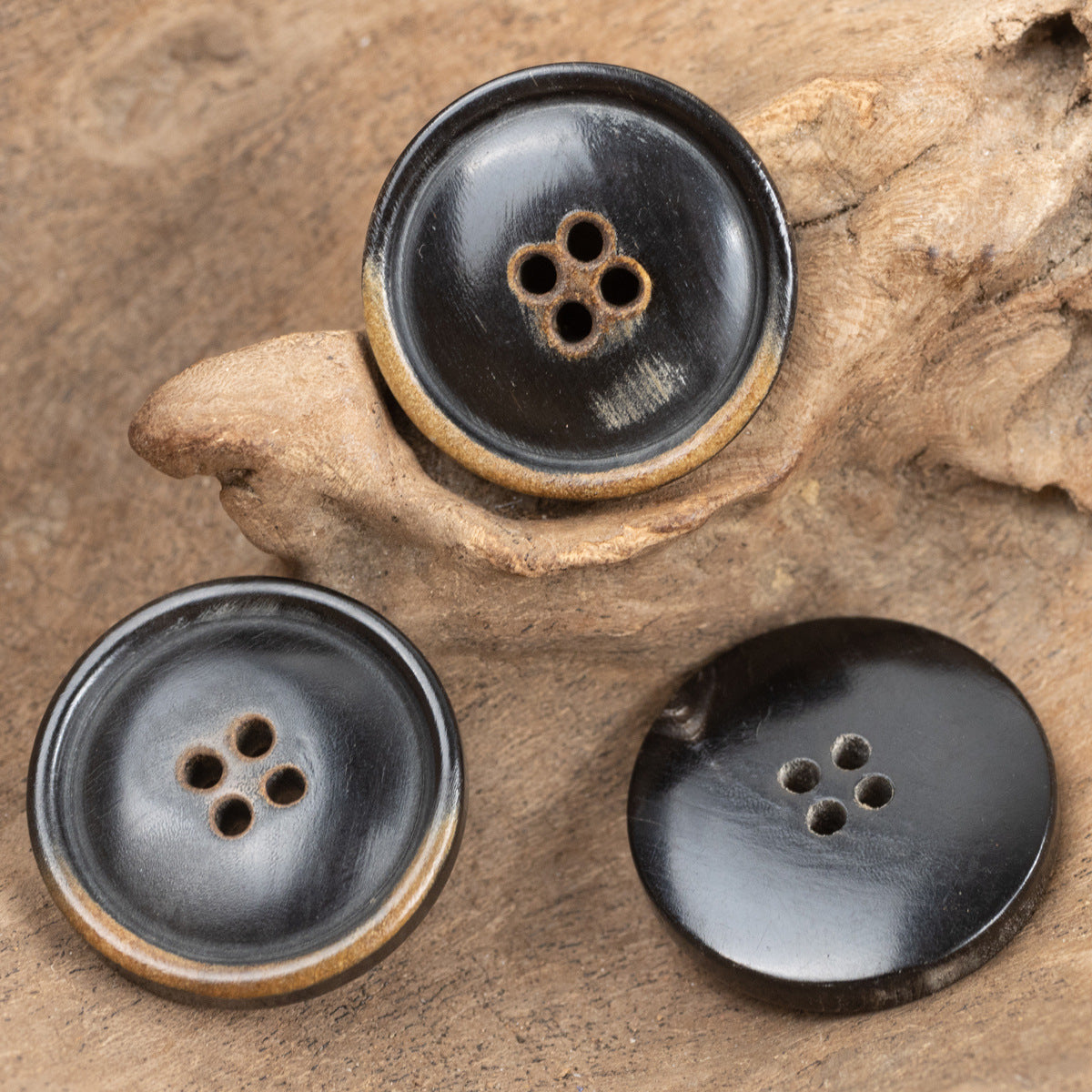 Set of three black four-hole clothing buttons with natural horn rim detail