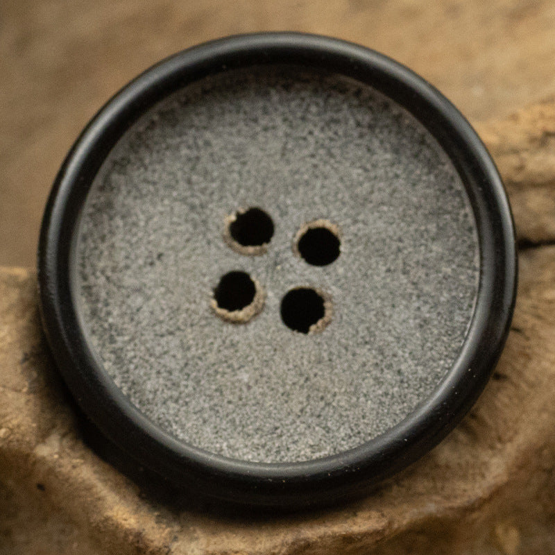 Silver Gray frosted horn button, close-up of four holes and dark edge