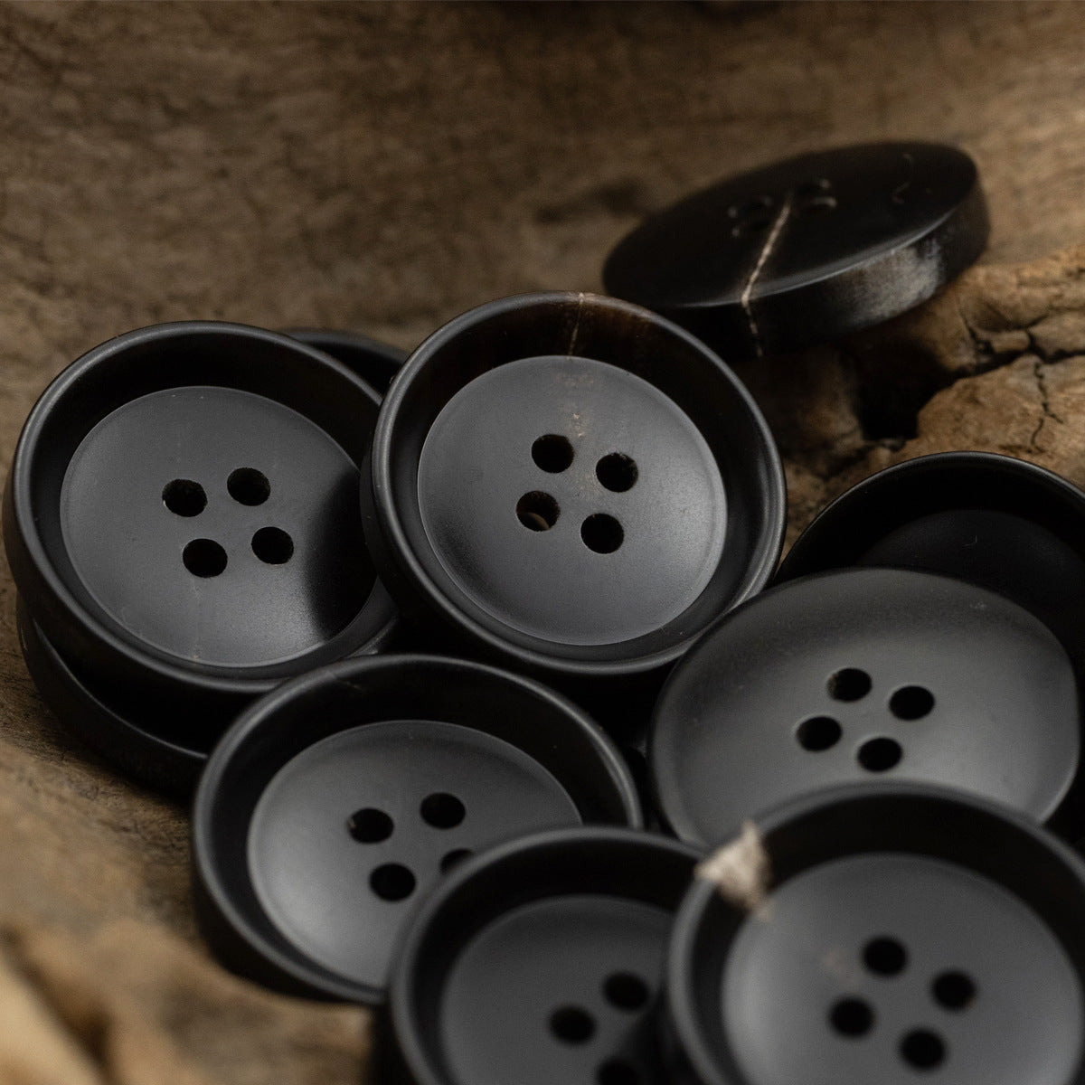 Dark-colored round 4-hole buttons, pan-shaped faces with four holes