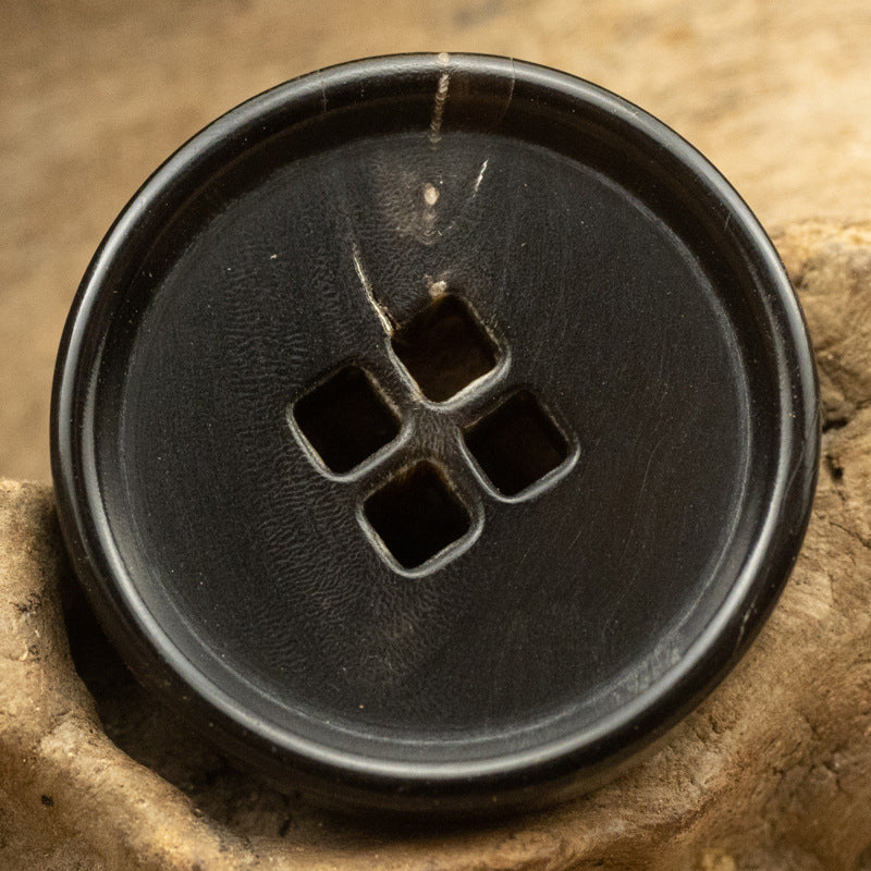 Black square-holed horn button, close-up front with four square holes