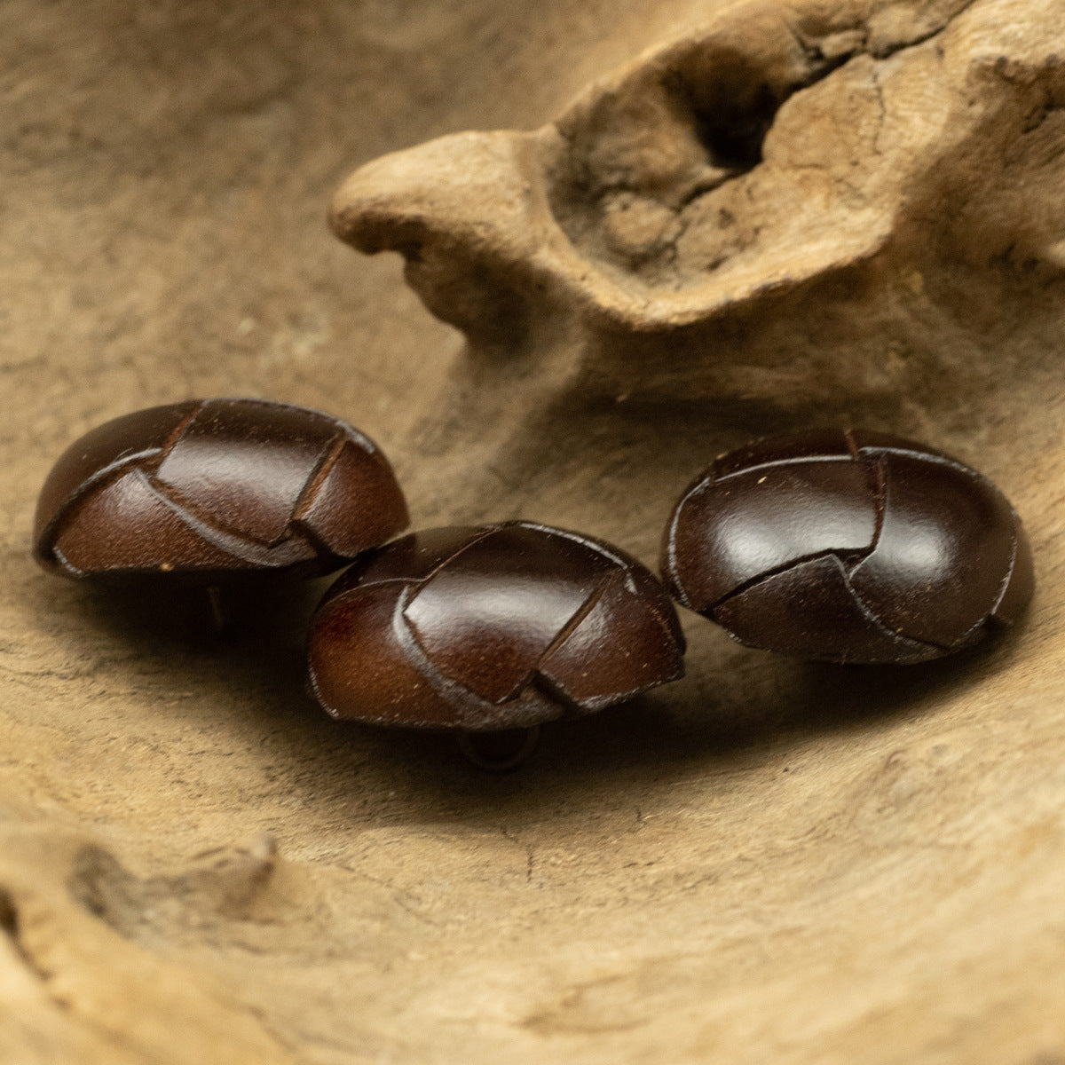 Dark brown woven leather spherical buttons with stitched cross-panel design