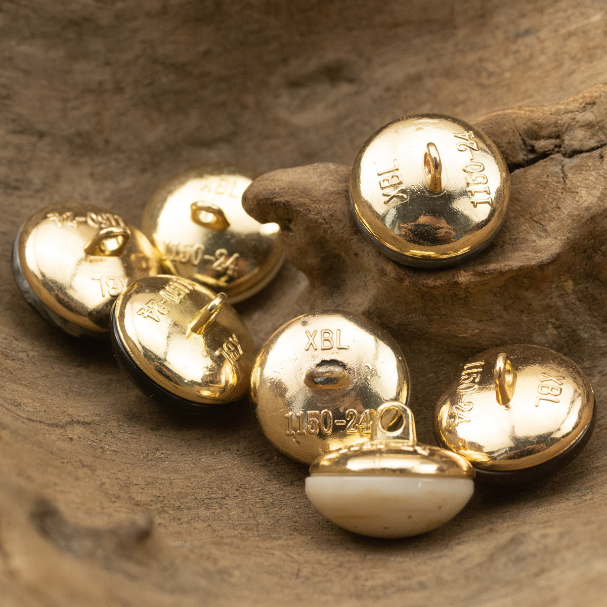 Gold metal backs of round cheongsam buttons with engraved markings and cream front tops
