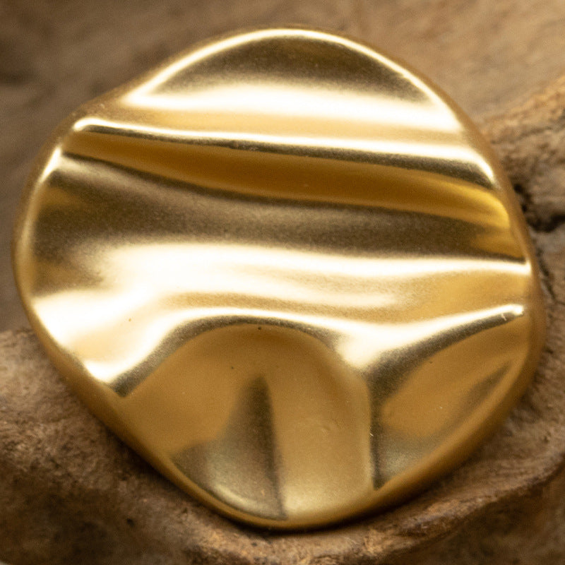 Matte geometric metal shank button in gold tone, rounded with diagonal stripe relief
