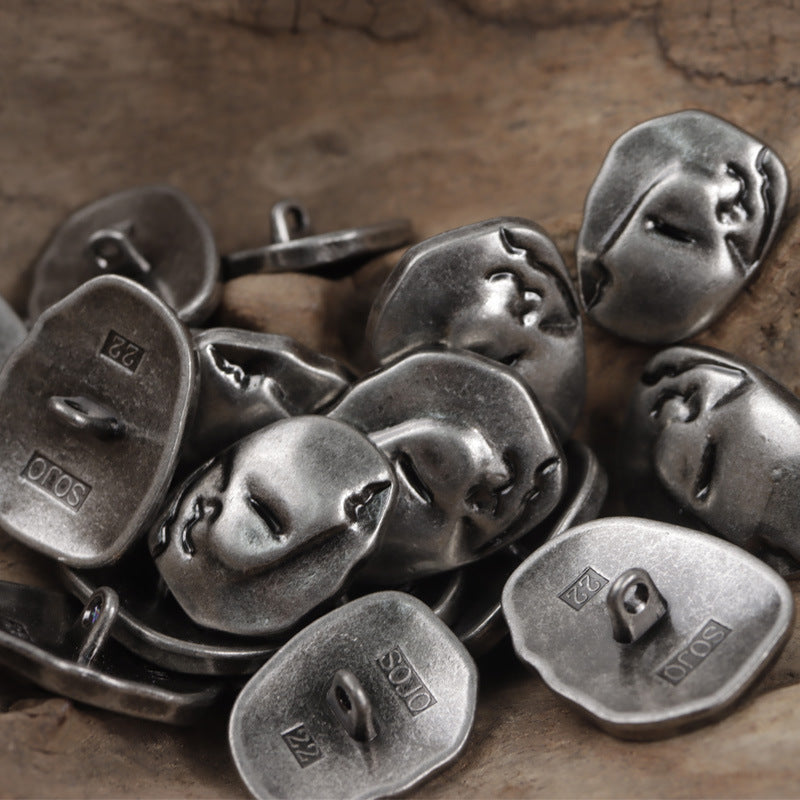 Dark metal face-motif buttons with shanks, irregular shapes and embossed facial features