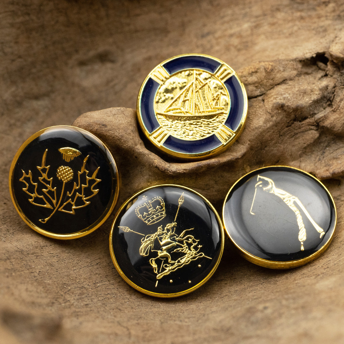 Metal shank buttons with gold engravings: camellia leaves, crown/horse, sailboat; dark glossy faces
