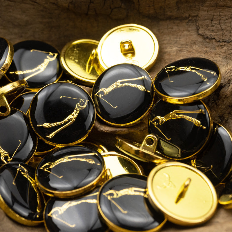 Metal shank buttons with gold engravings; several dark glossy faces and one pale button visible