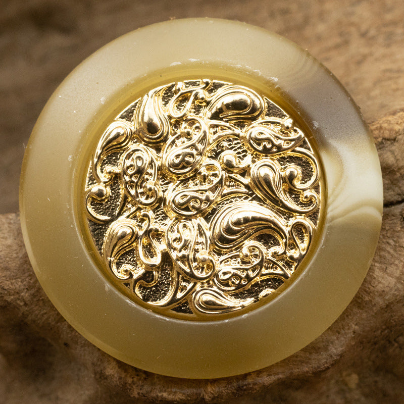 Light khaki resin button with gold cloud-style metal center, embossed ornamental design