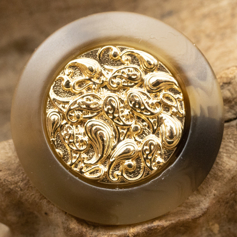 Deep khaki resin button with gold cloud-style metal center, intricate swirling ornament