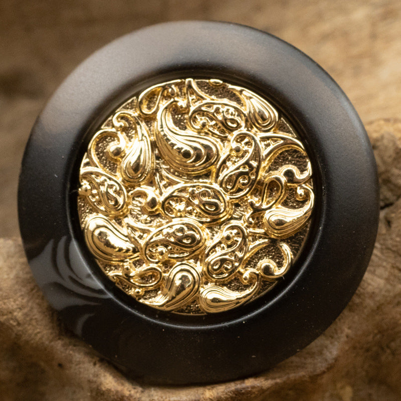 Black resin button with gold cloud-style metal center, ornate swirling pattern