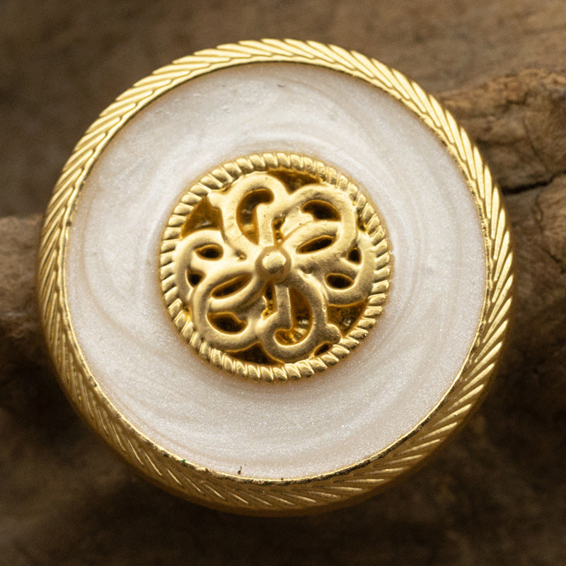 Pearl-glaze shank button in white with ornate gold filigree center and ridged rim