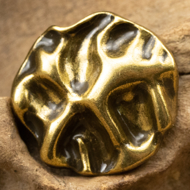 Bronze metal button with irregular wave-pattern surface and shank, close-up