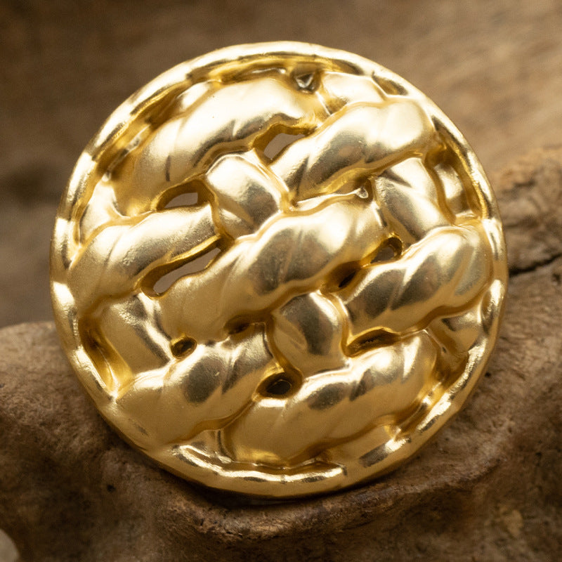 Gold twisted braided metal button, close-up round hammered texture, shank side