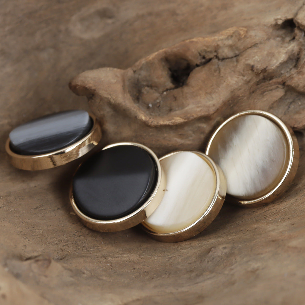 Round gold-tone shank buttons: deep gray and black fronts with cream/beige faces