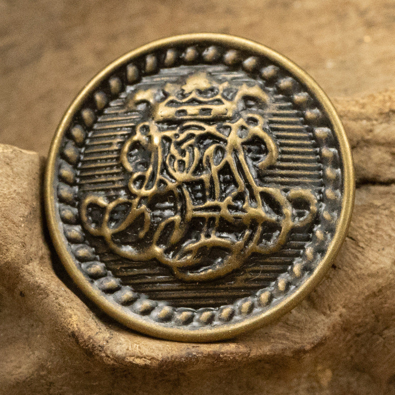 Round antique bronze brass button with detailed figure in ornate border