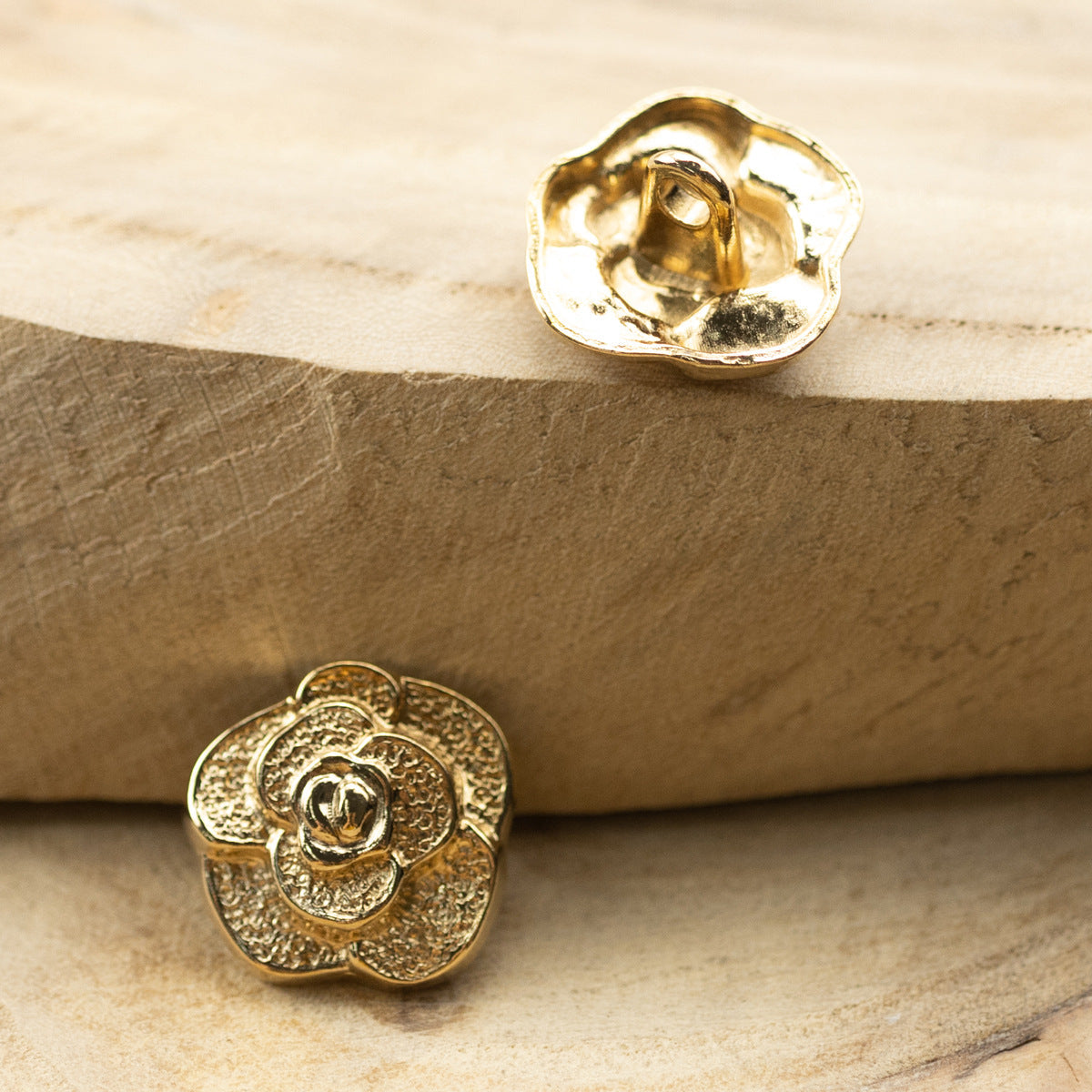 Single gold rose metal button, front view with textured petal border and center